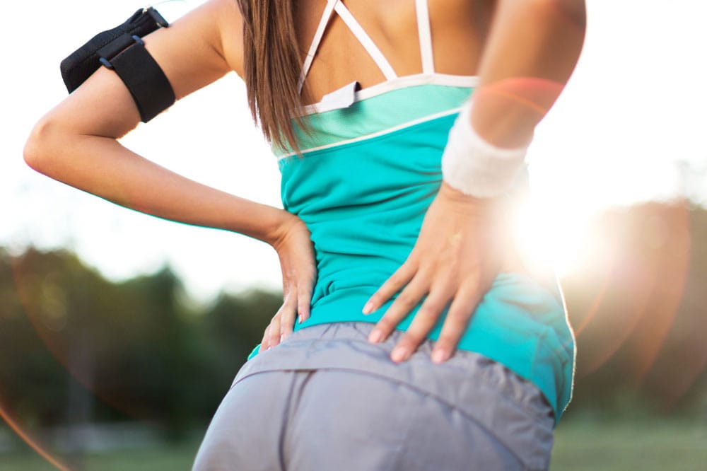 Frau macht eine Laufpause und hält ihre Hüften